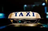 Close-up view of an illuminated taxi sign in a bustling city at night.